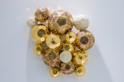 白い壁に掛けた、金と白の多面体の集まり（正面）